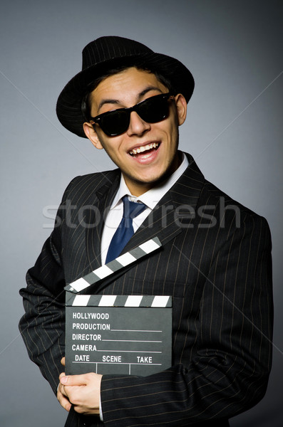 Young man in elegant suit holding clapperboard against gray Stock photo © Elnur