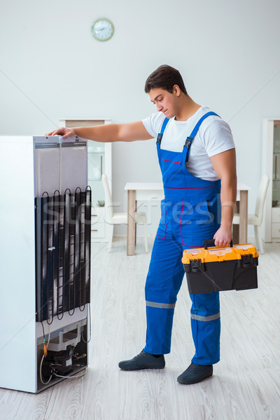 Stock photo: Repairman contractor repairing fridge in DIY concept