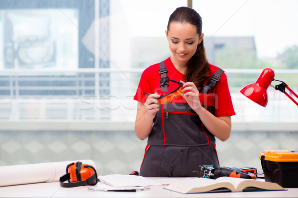 Stock photo: The young woman in coveralls doing repairs