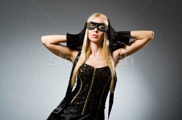 Stock photo: Woman wearing mask against dark background