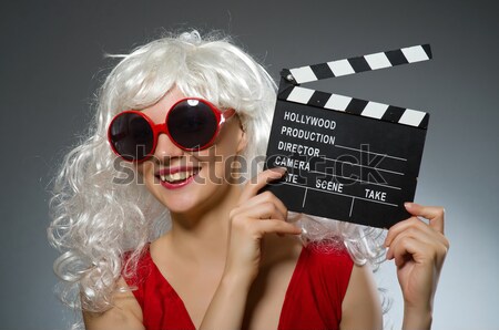 Stock photo: Girl with movie board against curtains