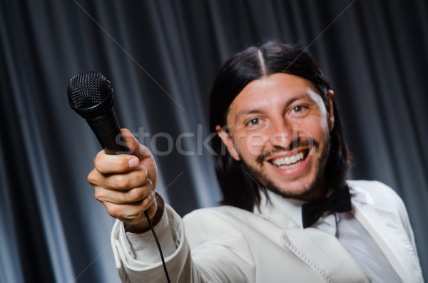 Stock photo: Man singing in front of curtain in karaoke concept