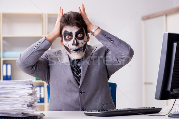 Businessmsn with scary face mask working in office Stock photo © Elnur