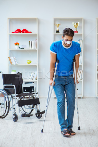 Young man recovering after surgery at home with crutches and a w Stock photo © Elnur