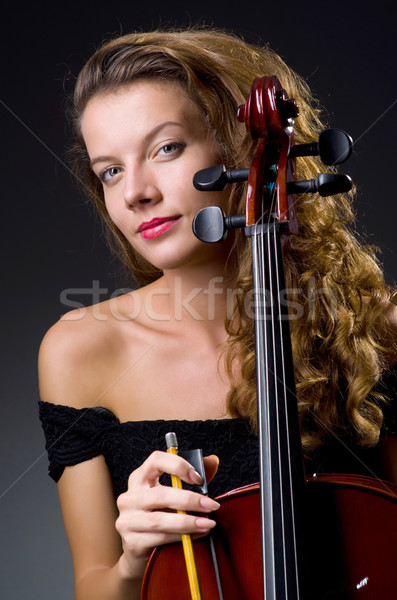 Stock photo: Female musical player against dark background