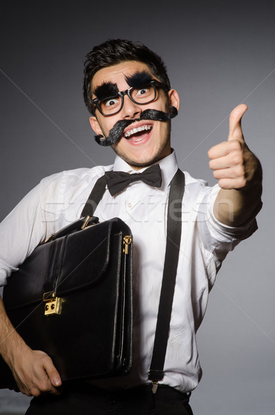 Young man with false moustache holding case  isolated on gray Stock photo © Elnur