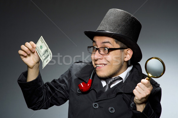 Stock photo: Young detective in black coat with money against gray