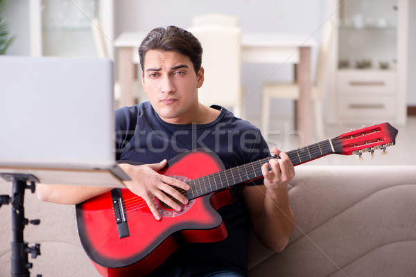 Young man practicing playing guitar at home Stock photo © Elnur