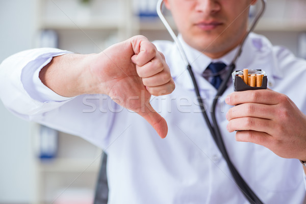Male doctor in anti-smoking conceptwithcigarette pack Stock photo © Elnur