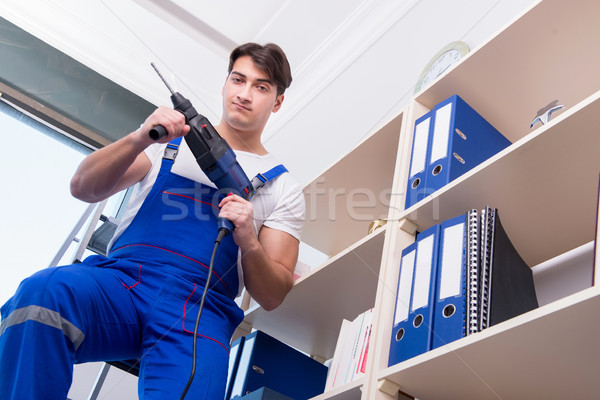Young worker repairing shelves in office Stock photo © Elnur