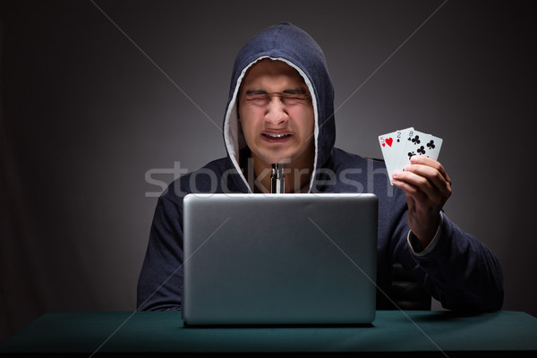 Young man wearing a hoodie sitting in front of a laptop computer Stock photo © Elnur