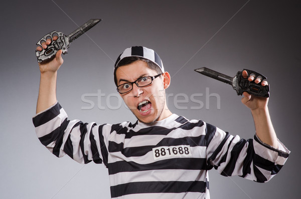 Young prisoner holding knifes against gray Stock photo © Elnur