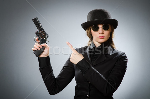 Female spy with weapon against gray Stock photo © Elnur