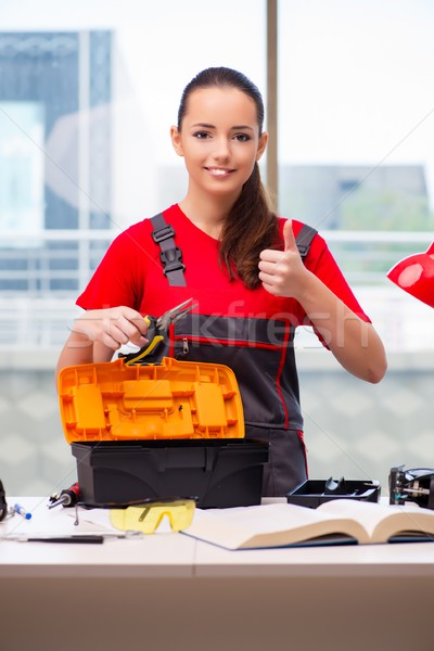 Stock photo: Young woman in coveralls doing repairs