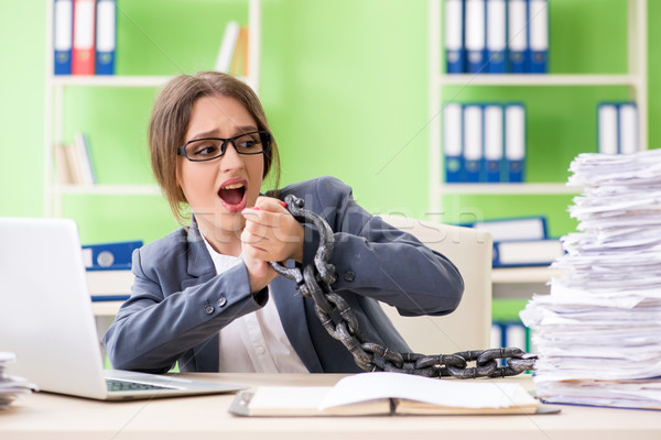 Stock photo: Young female employee  busy with ongoing paperwork chained to th