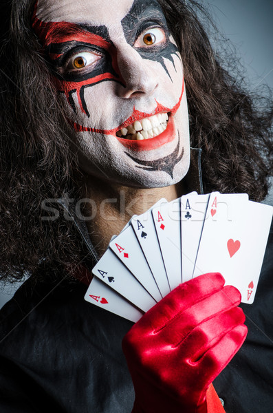 Stock photo: Evil clown with cards in dark room