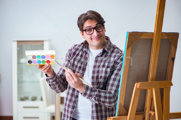 Young male artist drawing pictures in bright studio Stock photo © Elnur