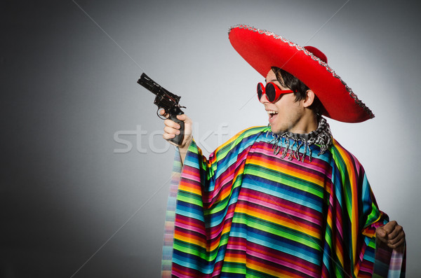 Man in vivid mexican poncho holding handgun against gray Stock photo © Elnur