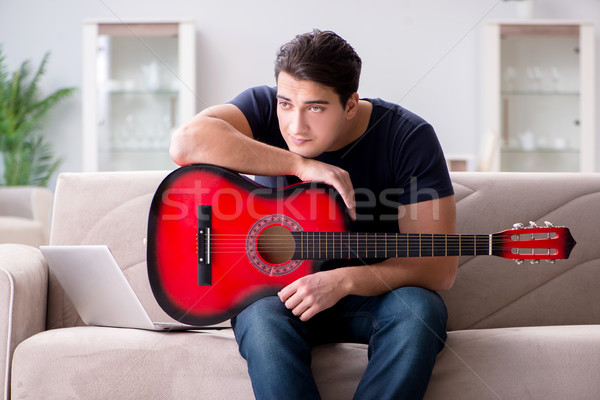Young man practicing playing guitar at home Stock photo © Elnur