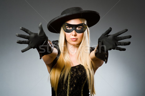 Stock photo: Woman wearing mask against dark background