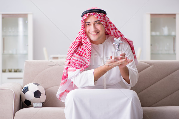 Stock photo: Young arab man watching football sitting on sofa