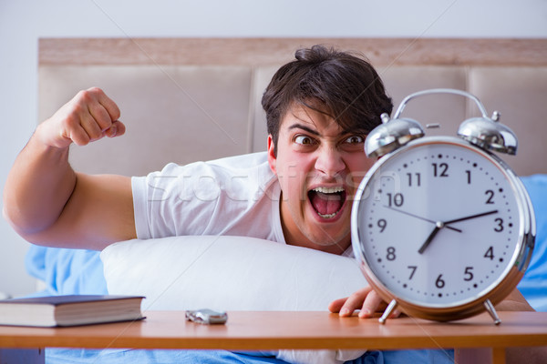 Man in bed frustrated suffering from insomnia with an alarm cloc Stock photo © Elnur