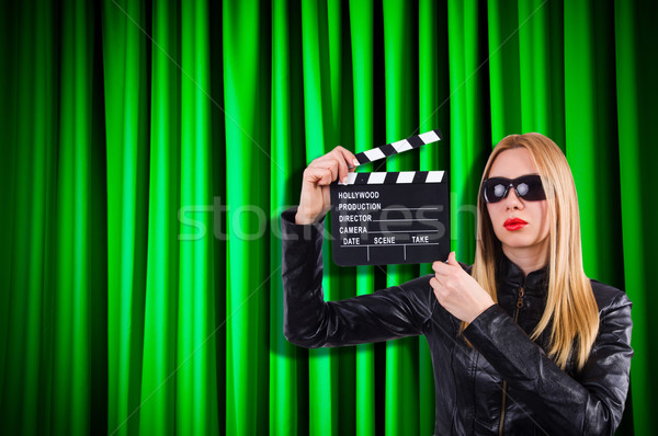 Stock photo: Girl with movie board against curtains