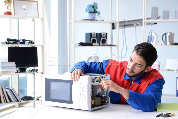 Young repairman fixing and repairing microwave oven Stock photo © Elnur