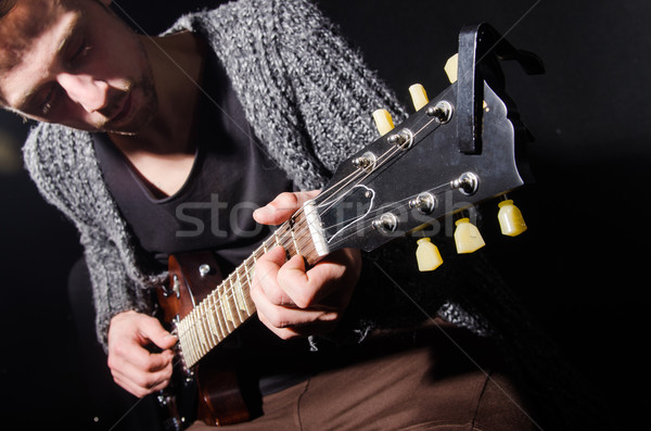 Stock photo: Man playing guitar in dark room