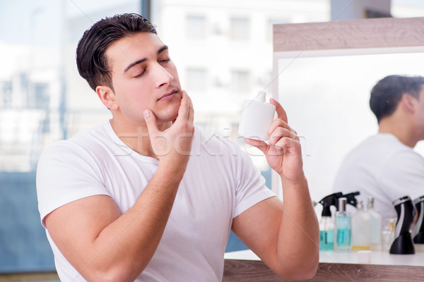 Young handsome man applying face cream Stock photo © Elnur