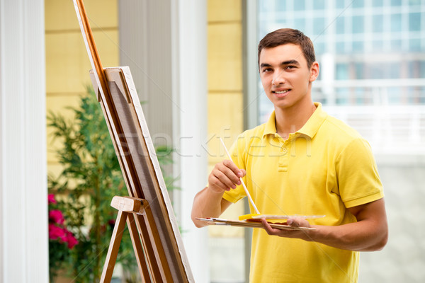 Young male artist drawing pictures in bright studio Stock photo © Elnur