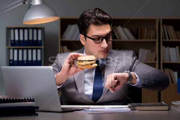 Stock photo: Businessman late at night eating a burger