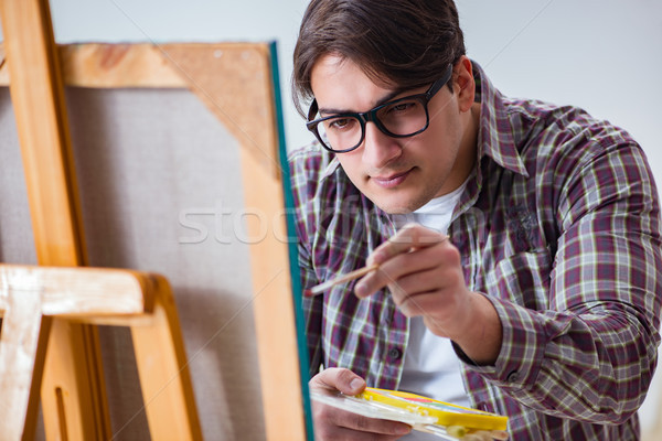 Young male artist drawing pictures in bright studio Stock photo © Elnur