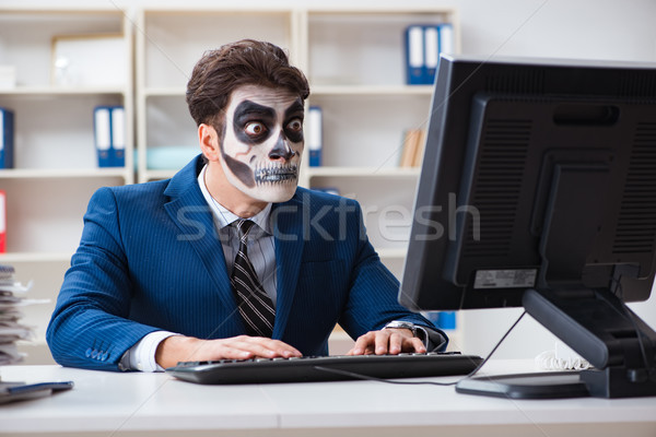 Businessmsn with scary face mask working in office Stock photo © Elnur