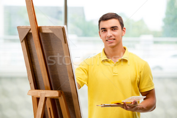 Young male artist drawing pictures in bright studio Stock photo © Elnur