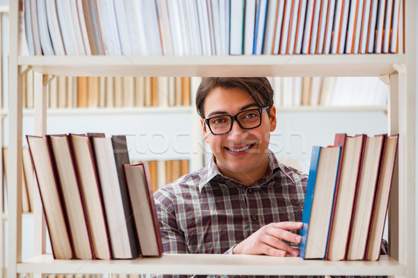 Młodych student patrząc książek kolegium biblioteki Zdjęcia stock © Elnur