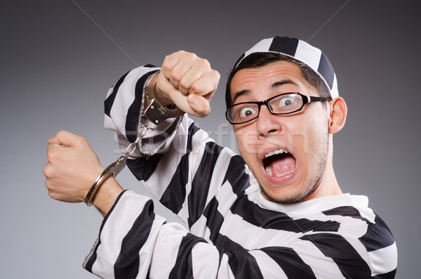 Stock photo: Young prisoner in handcuffs against gray
