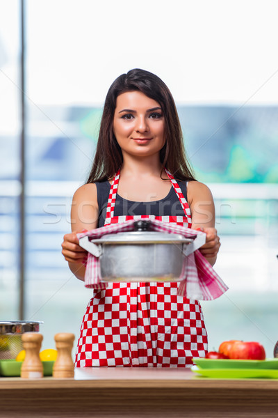 Female cook preparing soup in brightly lit kitchen Stock photo © Elnur