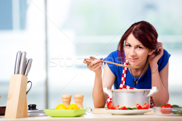 The female cook preparing soup in brightly lit kitchen Stock photo © Elnur