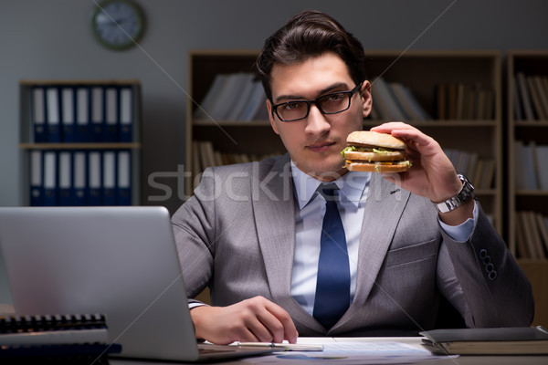 Stock photo: Businessman late at night eating a burger