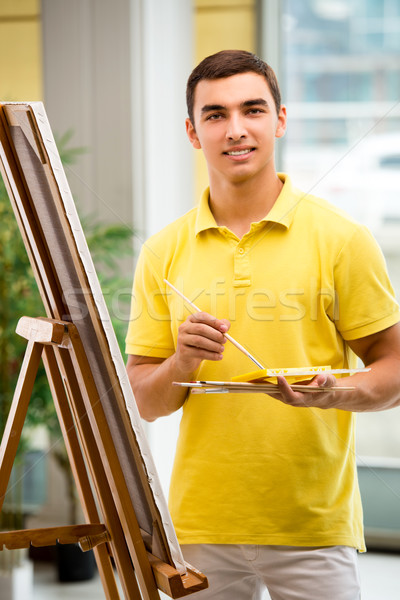 The young male artist drawing pictures in bright studio Stock photo © Elnur