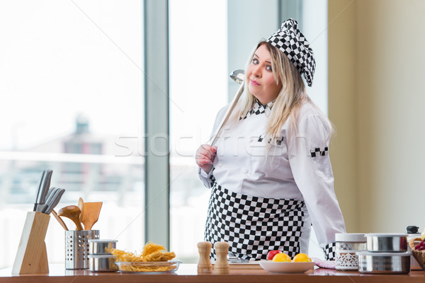 Female cook preparing soup in brightly lit kitchen Stock photo © Elnur