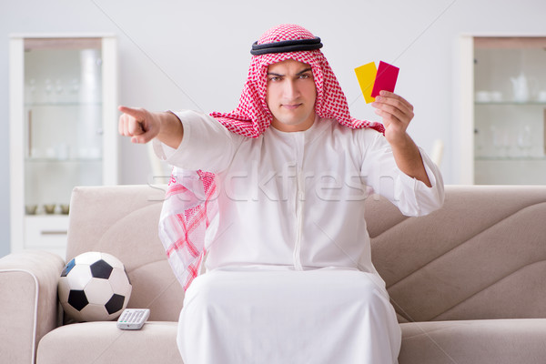 Stock photo: Young arab man watching football sitting on sofa