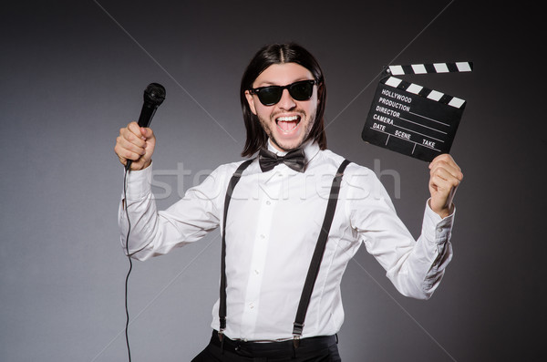 Positive man holding clapperboard and microphone isolated on gra Stock photo © Elnur