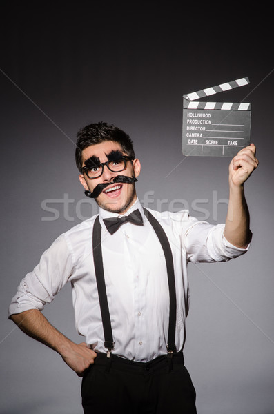 Young caucasian man with false moustache and clapperboard agains Stock photo © Elnur