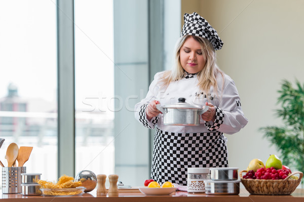 Female cook preparing soup in brightly lit kitchen Stock photo © Elnur