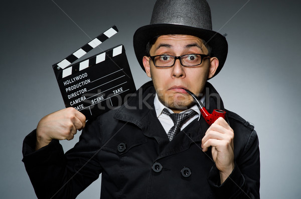 Detective in black coat with clapperboard against gray Stock photo © Elnur