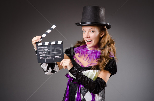 Pretty girl in jester costume holding clapperboard against gray Stock photo © Elnur