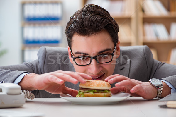 Stock photo: The hungry funny businessman eating junk food sandwich