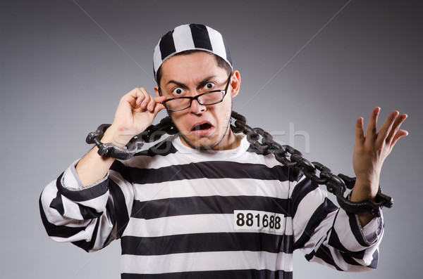 Stock photo: Young prisoner in chains against gray